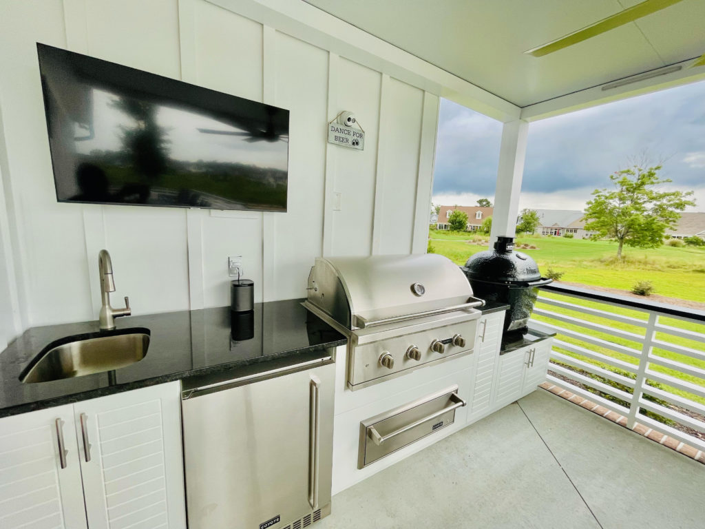 covered outdoor kitchen with grill, oven and charcoal smoker