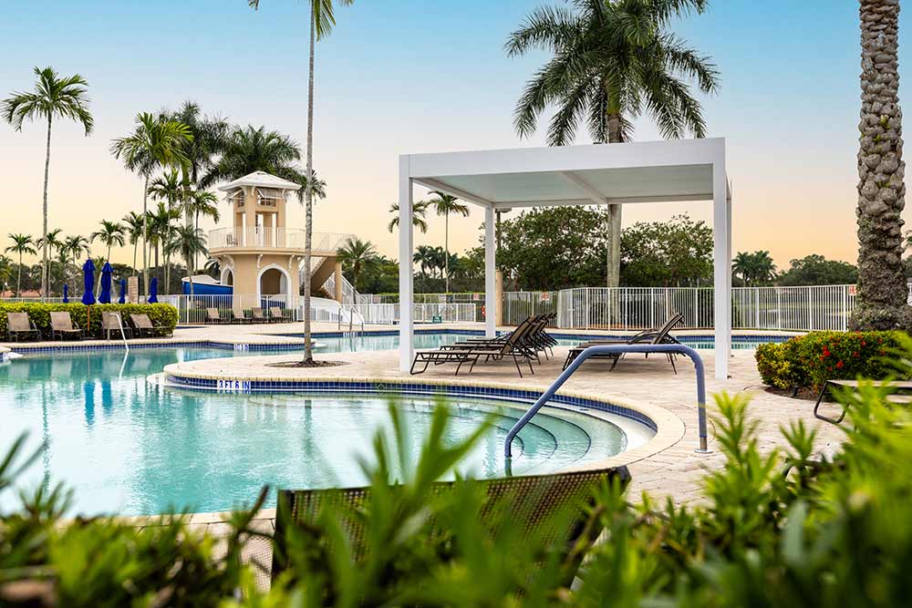 Covered lounging area at a community pool - R-SHADE pergola by Azenco