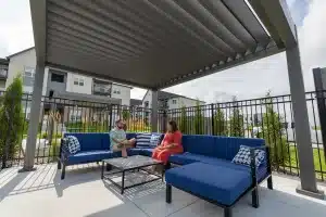 Gray louvered pergola with fireplace and stone patio at Tiburon Ridge Apartments in Omaha, NE