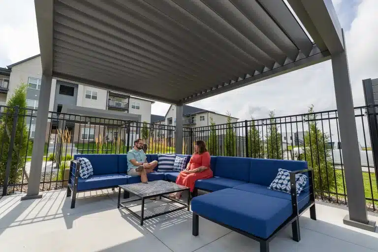 Gray louvered pergola with fireplace and stone patio at Tiburon Ridge Apartments in Omaha, NE
